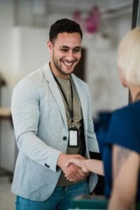 Smiling man and woman exchanging a handshake in a modern office environment.